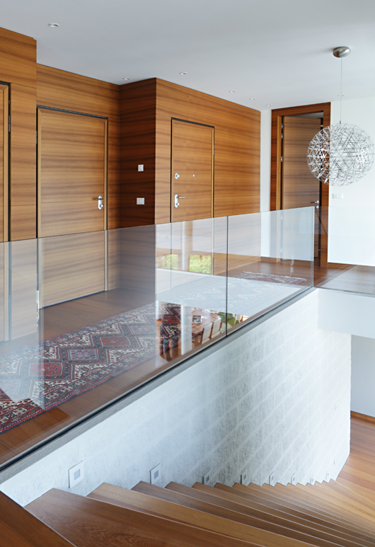 Glass railing on wall with wooden doors.