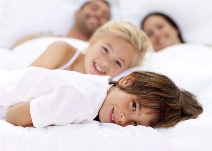 Young family resting together in parent's bed